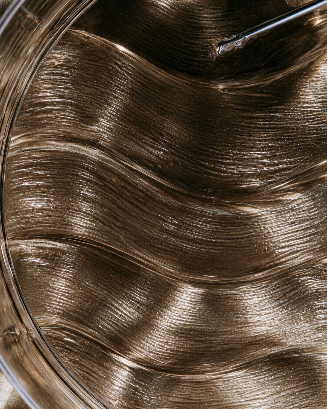 Combed waves of translucent glycerin catching warm light